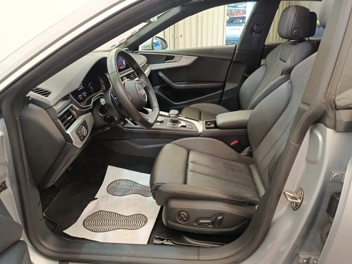 Intérieur avant droit d'Audi A5 gris clair 2019, sièges cuir noirs et tableau de bord moderne avec volant multifonction.