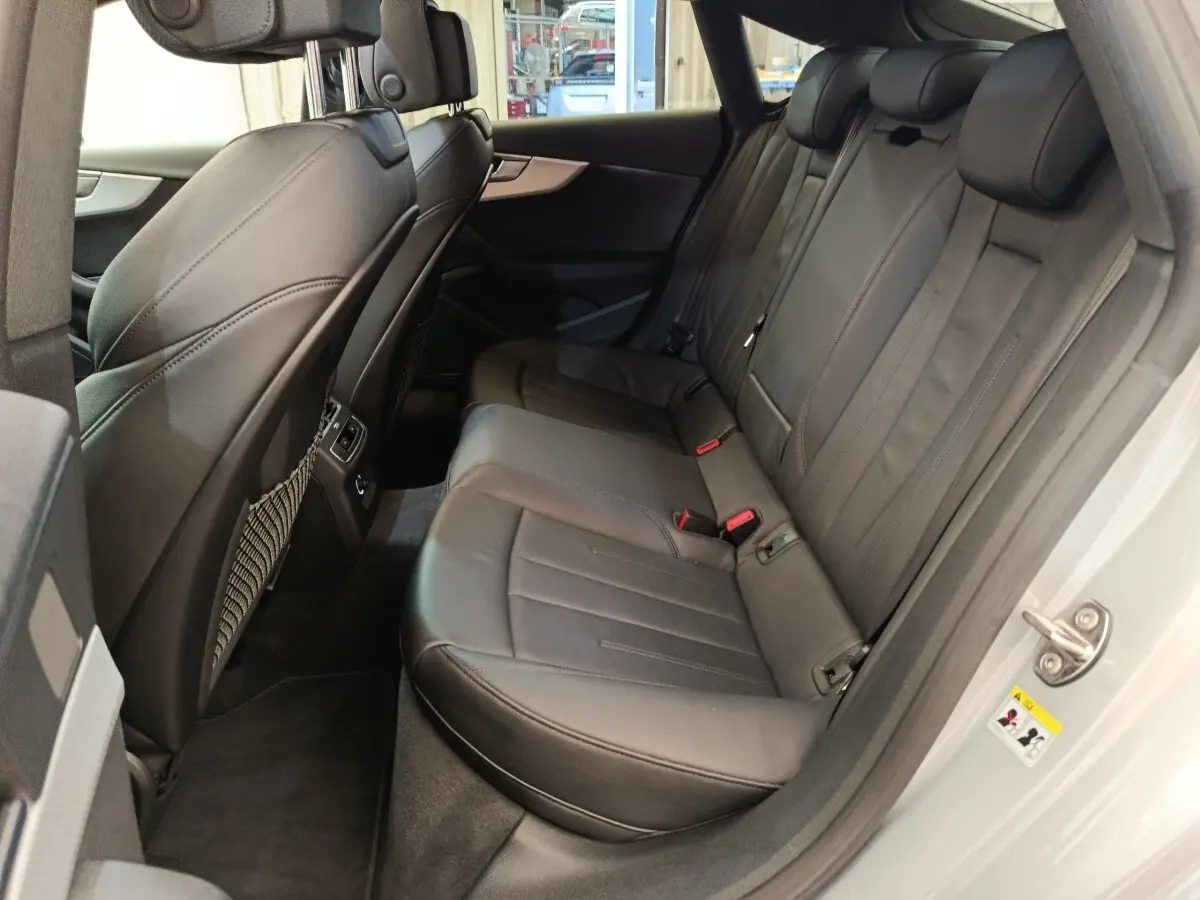 Vue côté droit de la banquette arrière en cuir noir de l'Audi A5 gris clair, avec ceintures et appuie-têtes visibles.
