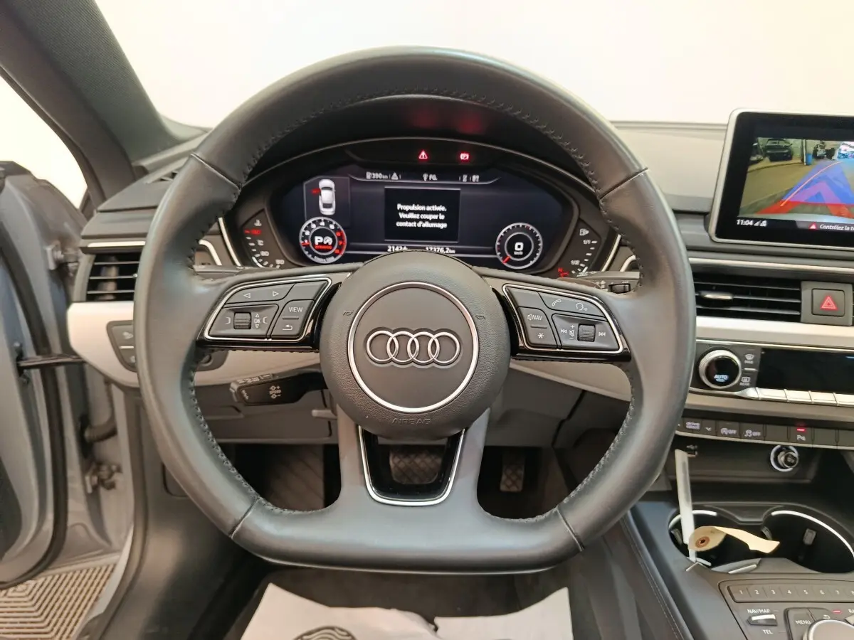 Vue centrée sur le volant cuir noir de l'Audi A5 40 TFSI 2019 avec tableau de bord digital et écran multimédia.
