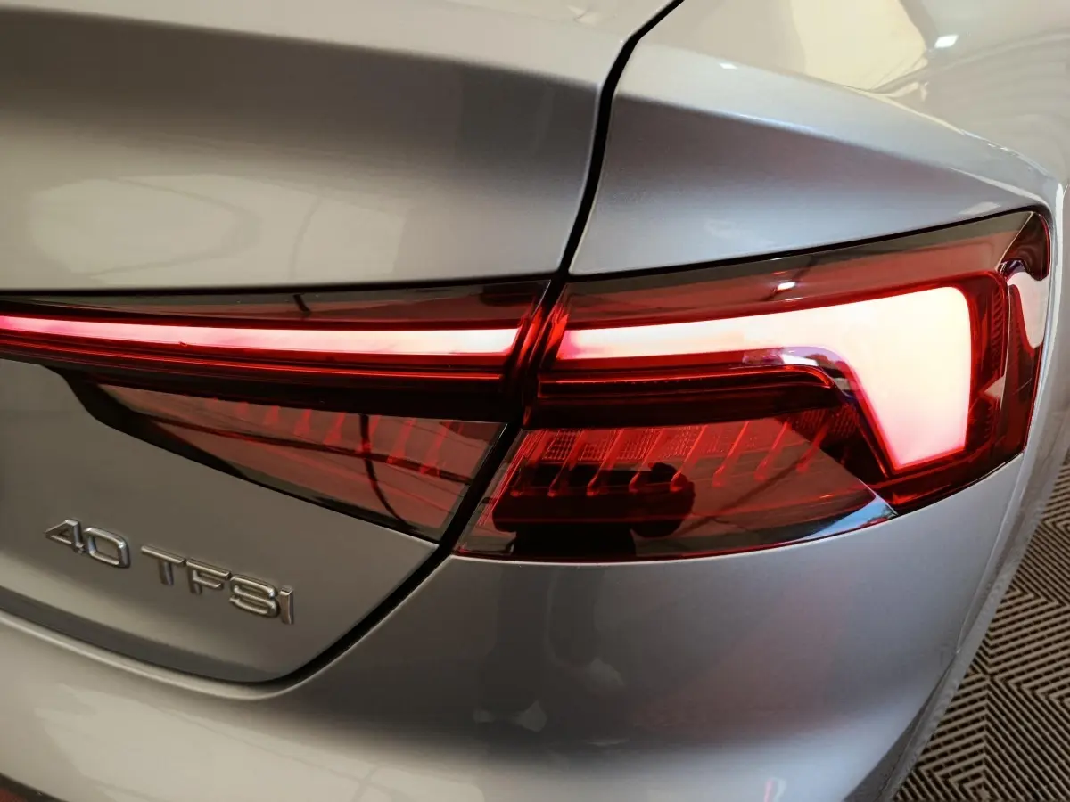 Gros plan sur le feu arrière droit rouge et le logo 40 TFSI d’une Audi A5 gris clair de 2019.