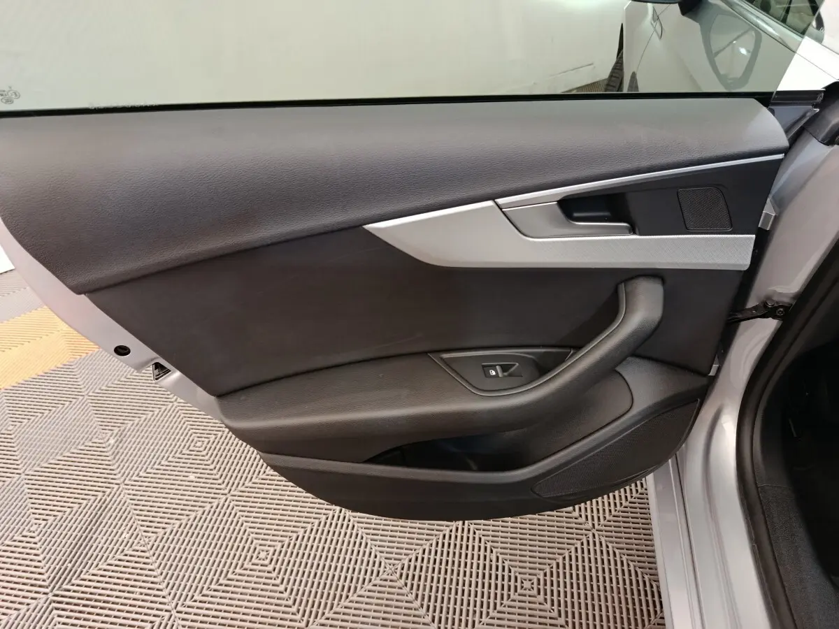 Vue intérieure de la porte avant gauche d'une Audi A5 gris clair, avec garniture noire et insert argenté.