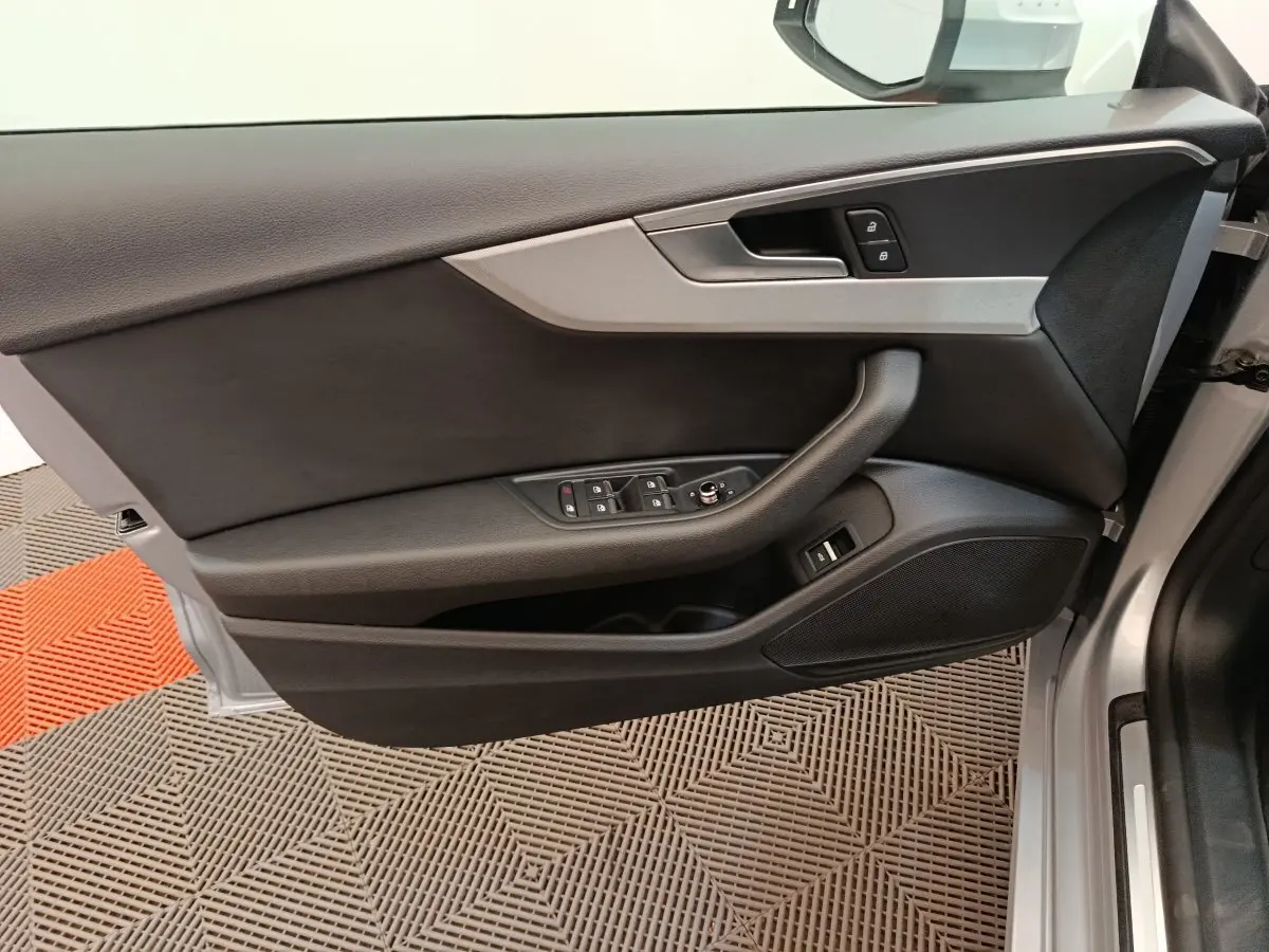 Vue intérieure sur la porte avant gauche gris clair de l'Audi A5 40 TFSI avec commandes de vitres et verrouillage.