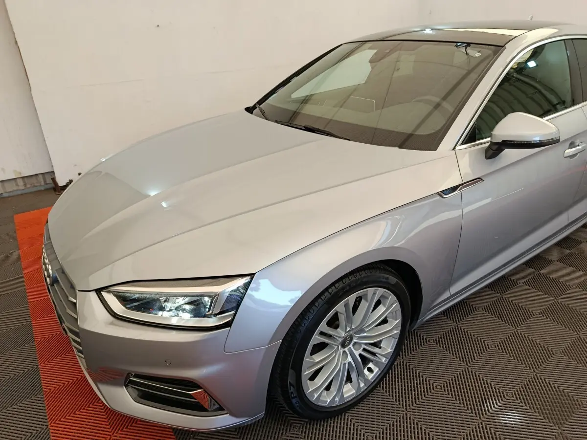 Audi A5 gris clair vue 3/4 avant droit, mettant en valeur les phares LED et la calandre distinctive.