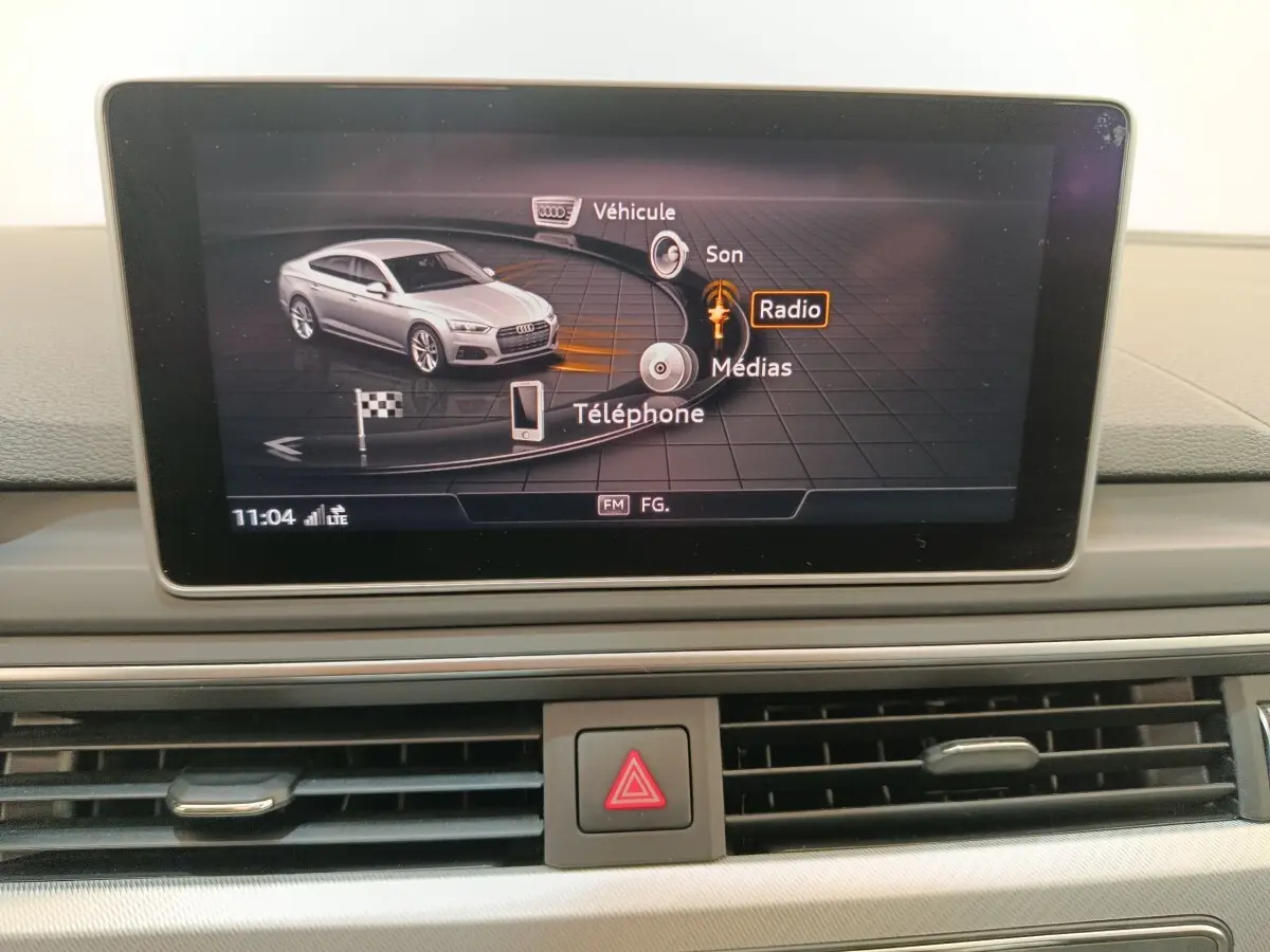 Écran multimédia affichant une Audi A5 gris clair vue de profil dans le menu principal du système de navigation.