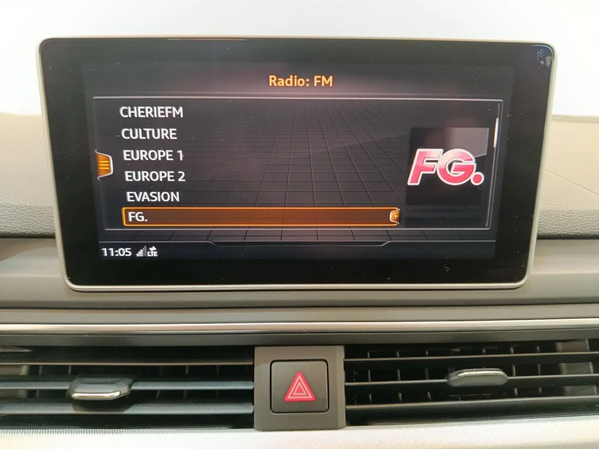 Écran central de l’Audi A5 2019 affichant la liste des stations radio FM, avec tableau de bord gris clair visible.