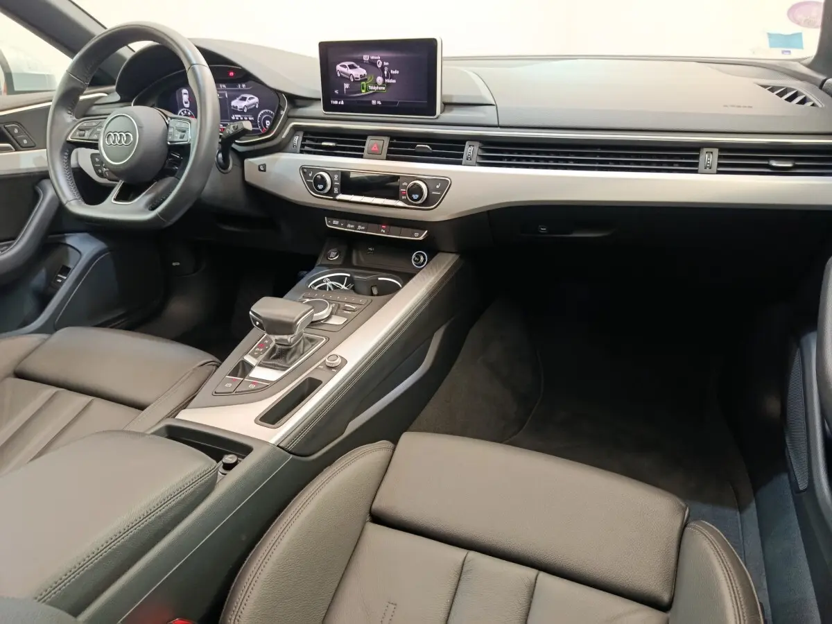 Vue intérieure côté conducteur de l'Audi A5 40 TFSI 2019, tableau de bord moderne avec écran central et volant cuir multifonctions.