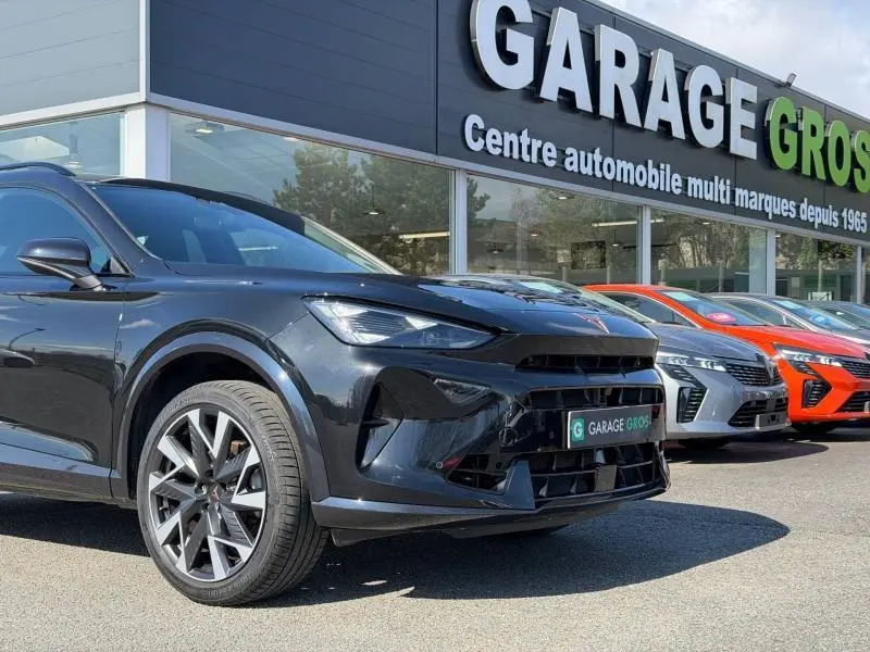 Vue 3/4 avant droite du CUPRA Formentor 1.5 eTSI Hybrid 2025 en Noir Minuit métallisé, devant un garage multimarques.