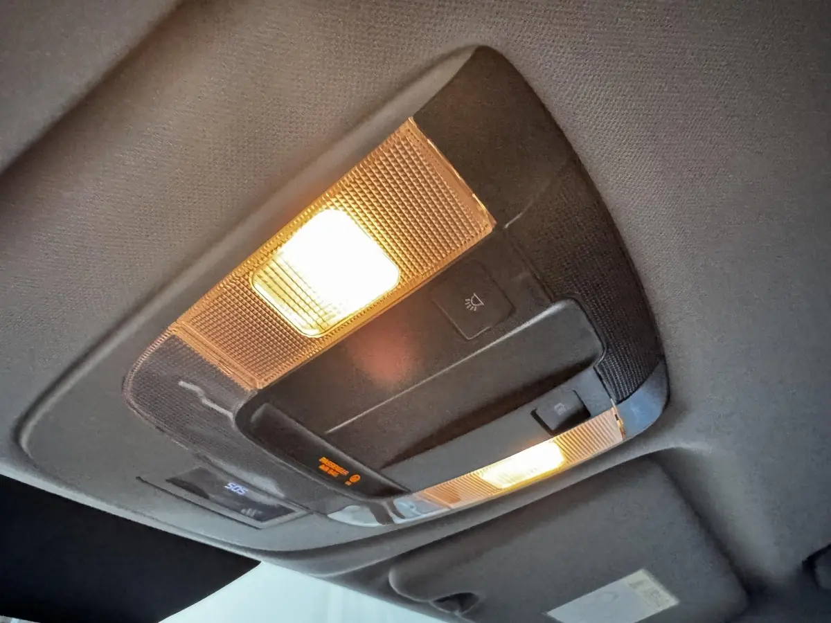 Plafonnier intérieur allumé du Kia Sportage blanc 2024, vue en léger contre-plongée sur la console de toit.