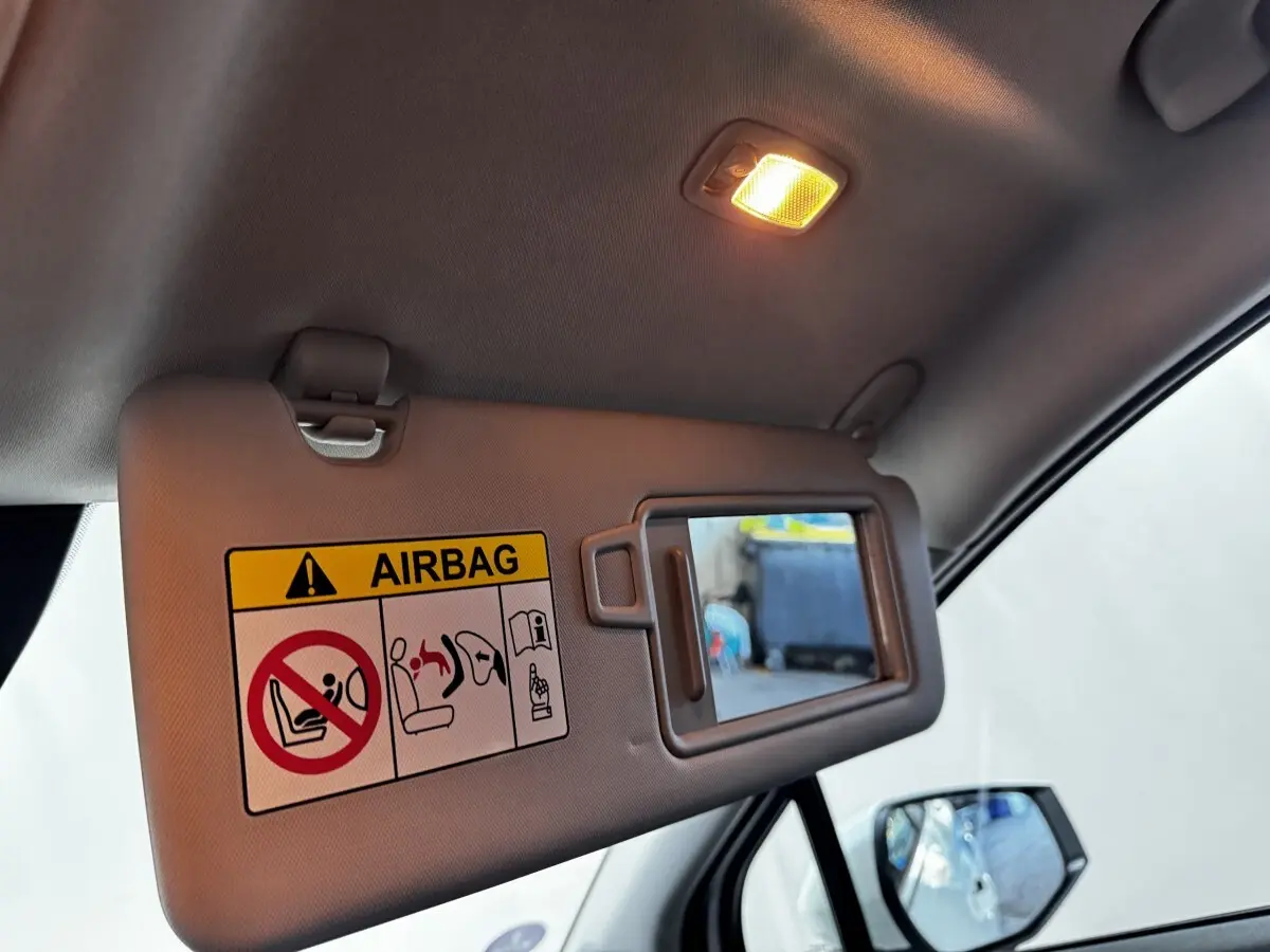 Détail intérieur du pare-soleil côté conducteur avec miroir et avertissement airbag dans un Kia Sportage blanc.