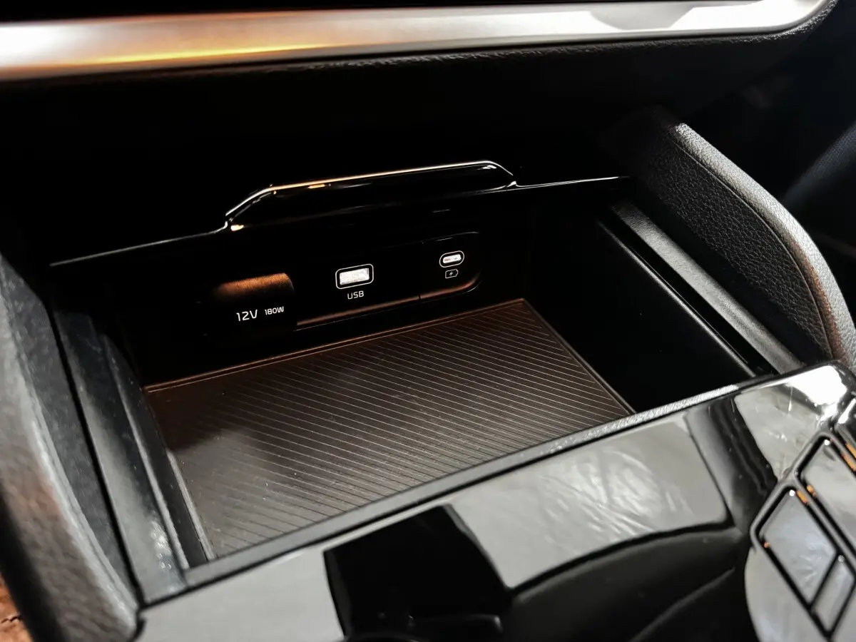 Détail de la console centrale noire du Kia Sportage 2024 avec prises USB et 12V visibles en gros plan.