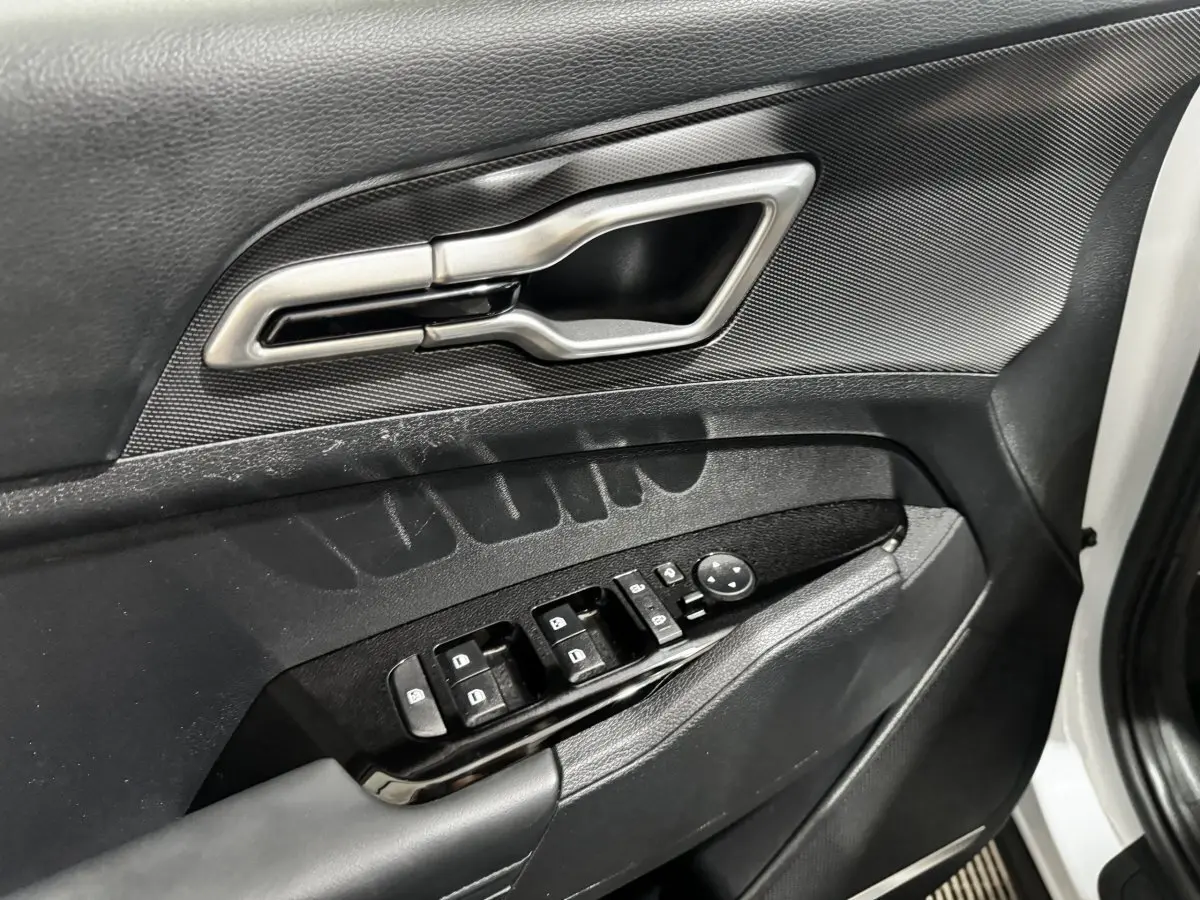Gros plan sur la porte avant gauche blanche du Kia Sportage 2024, montrant la poignée argentée et les commandes de vitres noires.