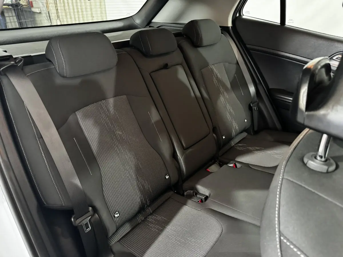 Vue intérieure côté arrière droit montrant la banquette noire avec appuie-têtes et ceinture de sécurité du Kia Sportage 2024 blanc.