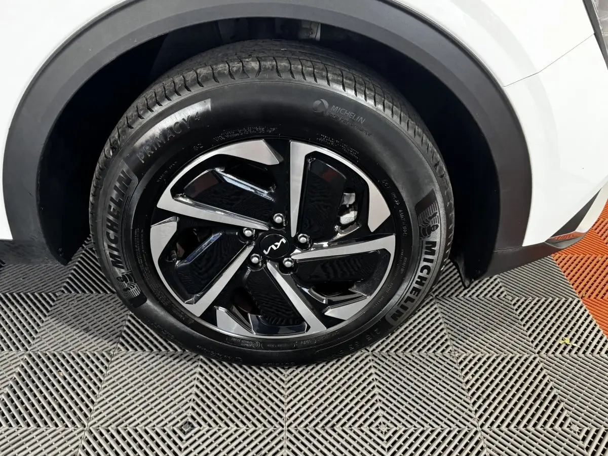 Gros plan sur la roue avant droite du KIA Sportage blanc, avec jante noire et argent et pneu Michelin.