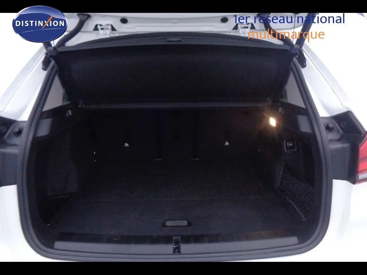 Coffre ouvert d'un BMW X1 blanc Alpine Metal, vue arrière montrant l'espace de chargement intérieur sombre.