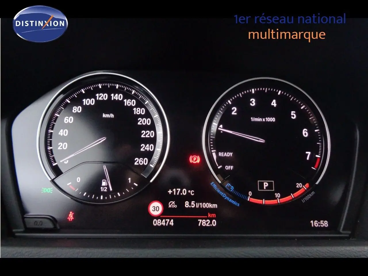 Tableau de bord numérique de BMW X1 blanc Alpine, affichant vitesse, régime moteur et informations de conduite.