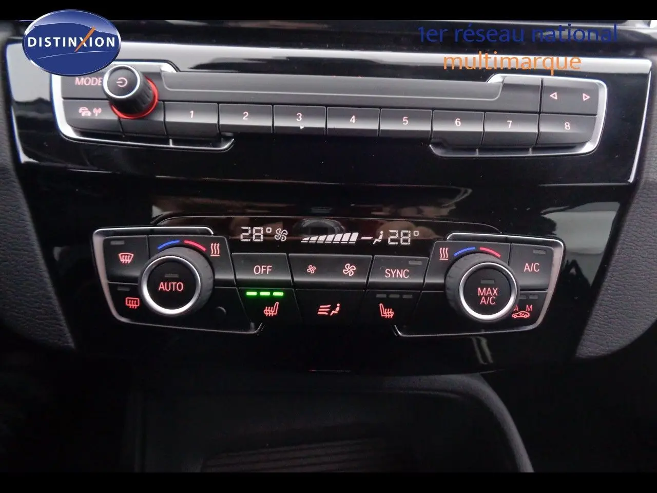 Tableau de bord du BMW X1 blanc Alpine Metal 2022 montrant les commandes de climatisation automatique et chauffage des sièges.