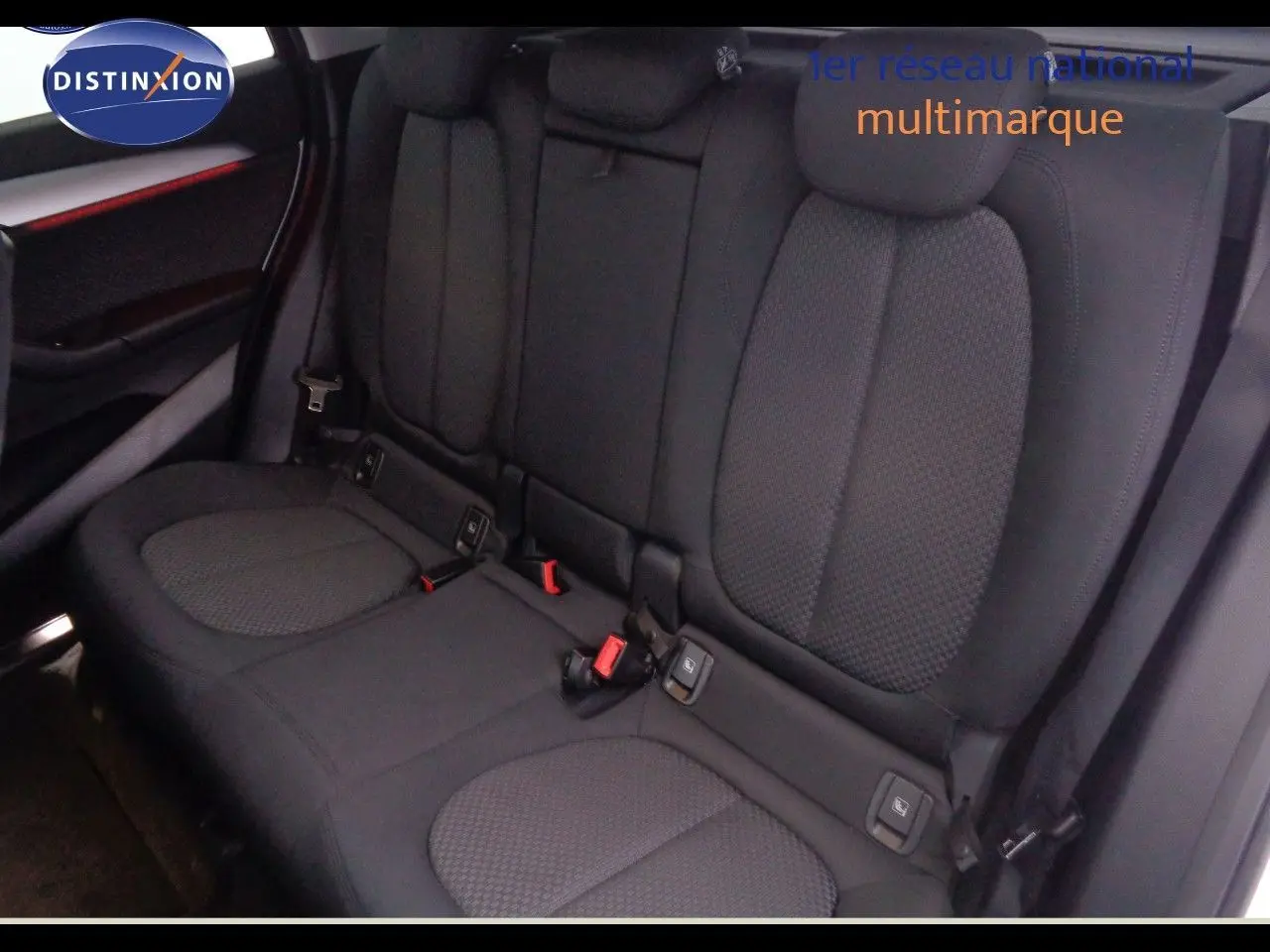 Vue intérieure arrière des sièges noirs en tissu du BMW X1 2022, mettant en valeur les appuie-têtes et ceintures de sécurité.