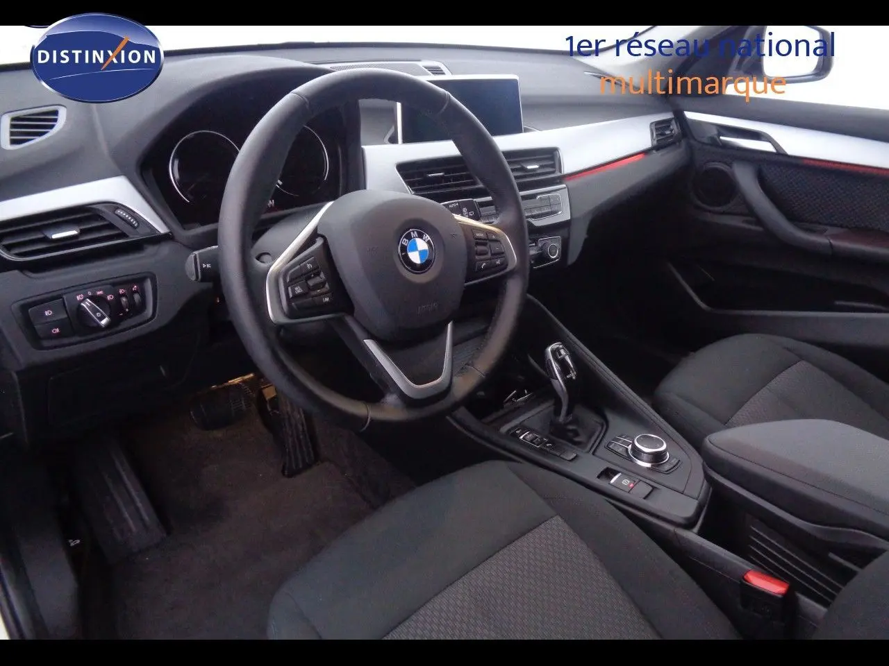 Intérieur avant droit d'une BMW X1 2022 avec volant multifonction, sellerie noire et console centrale moderne.