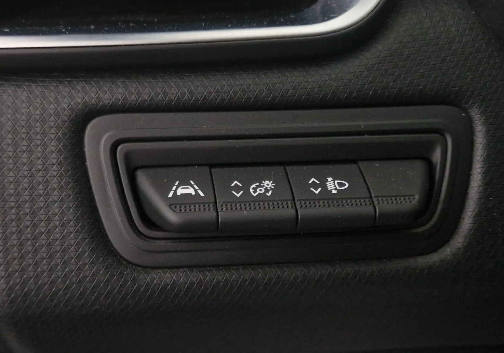 Gros plan sur les boutons de réglage d'assistance et d'éclairage dans une Renault Clio V gris platine de 2021.