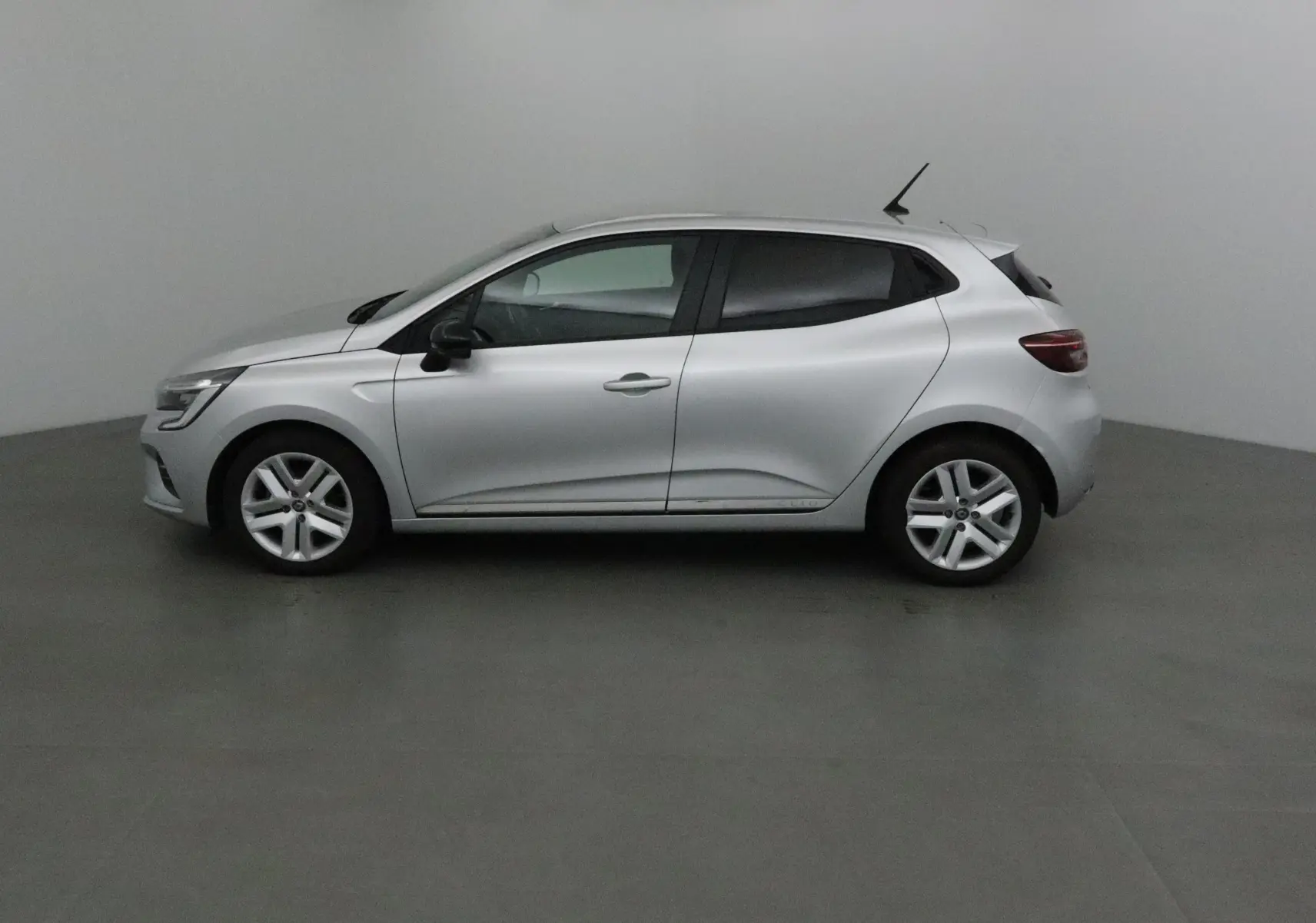 Profil côté gauche d'une Renault Clio V gris platine 2021, compacte et moderne avec lignes fluides et jantes alliage.