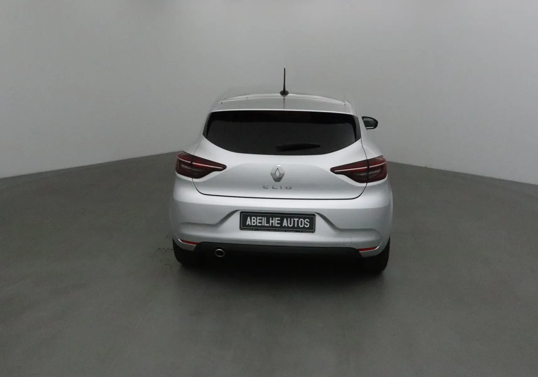 Vue arrière d'une Renault Clio V gris platine 2021 avec feux LED et plaque Abeilhe Autos visible.