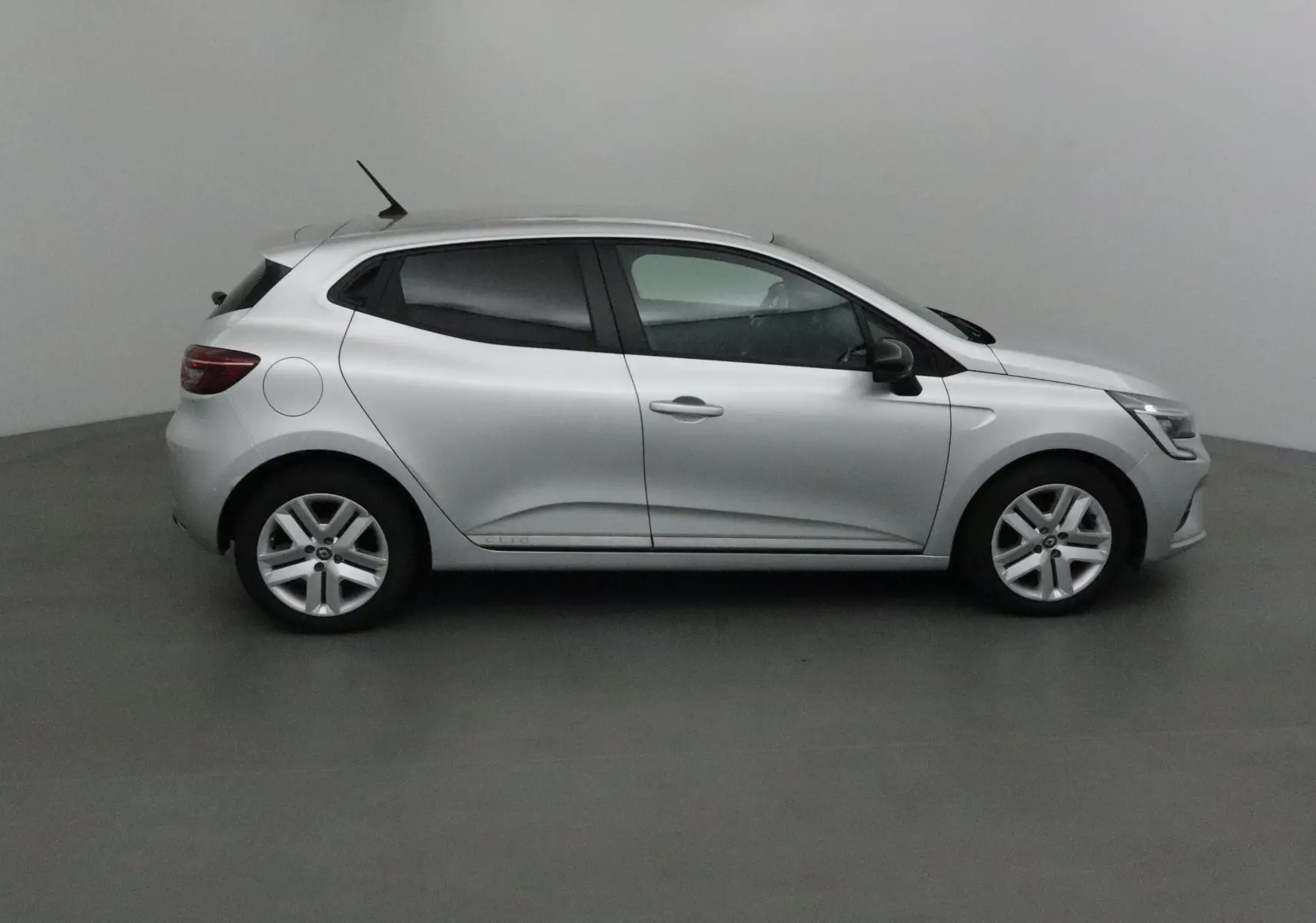Profil côté gauche d'une Renault Clio V gris platine de 2021, compacte et moderne avec jantes alliage visibles.