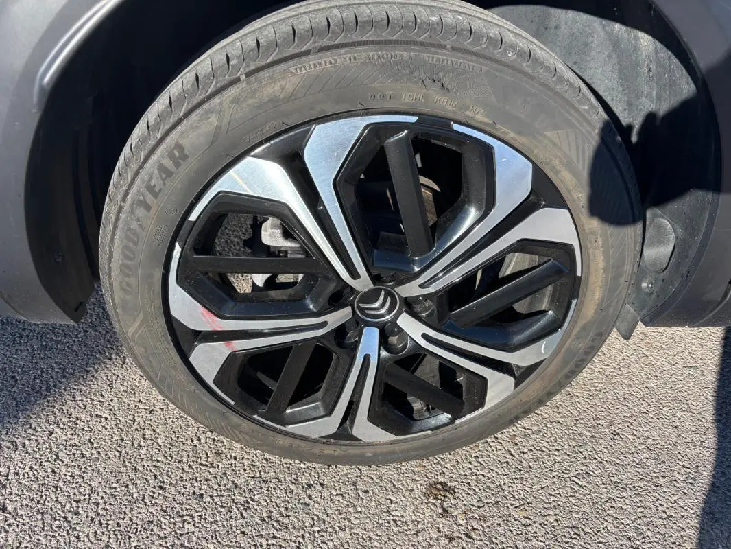 Gros plan sur la jante alliage 19 pouces noire et argentée du Citroën C5 X gris foncé, vue côté roue avant.