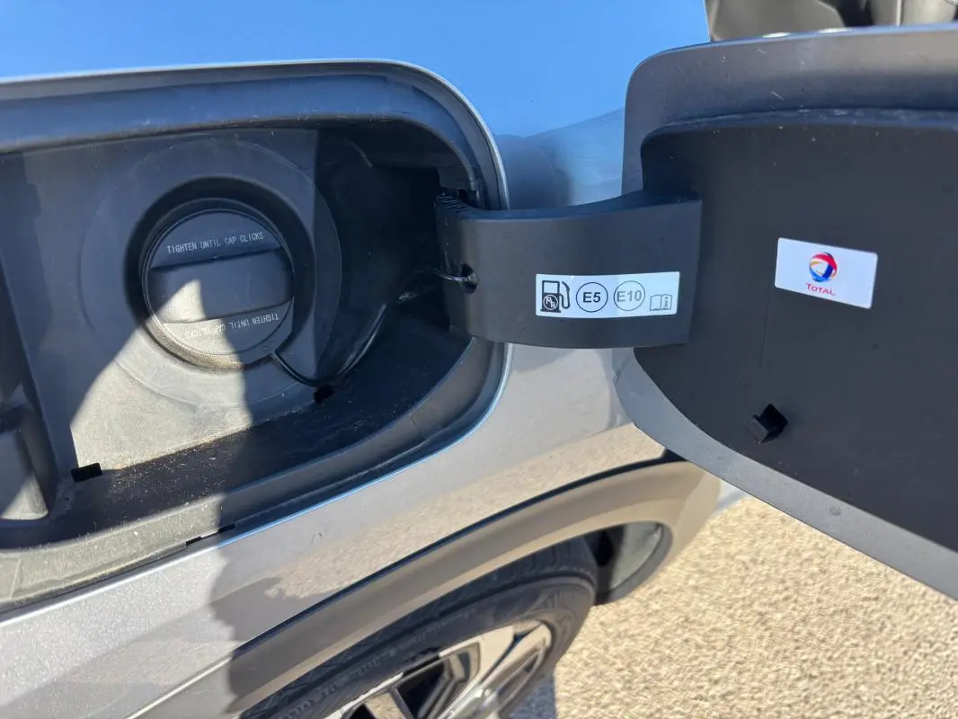 Gros plan sur la trappe à carburant ouverte côté gauche d’une Citroën C5 X gris foncé, avec bouchon essence visible.