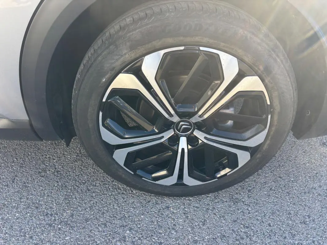 Gros plan sur la jante alliage 19 pouces noire et argentée d'une Citroën C5 X gris foncé, côté roue avant.