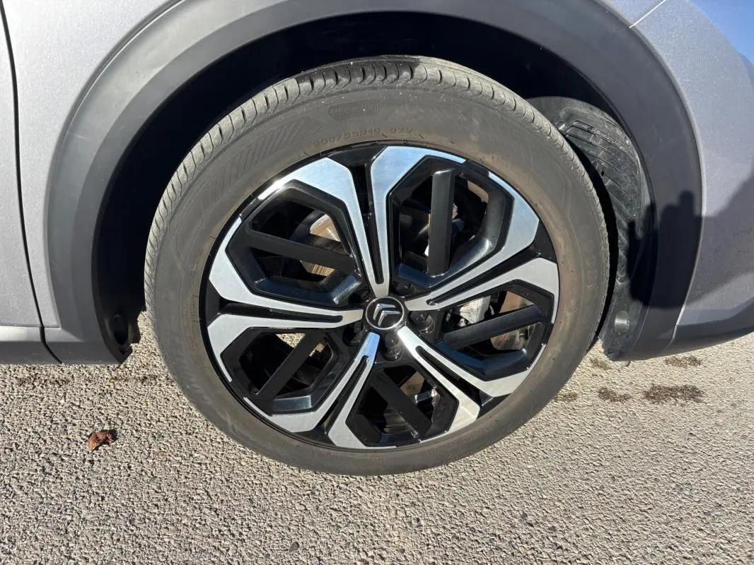 Gros plan sur la jante alliage 19 pouces noire et argentée du côté avant droit d'une Citroën C5 X gris foncé.