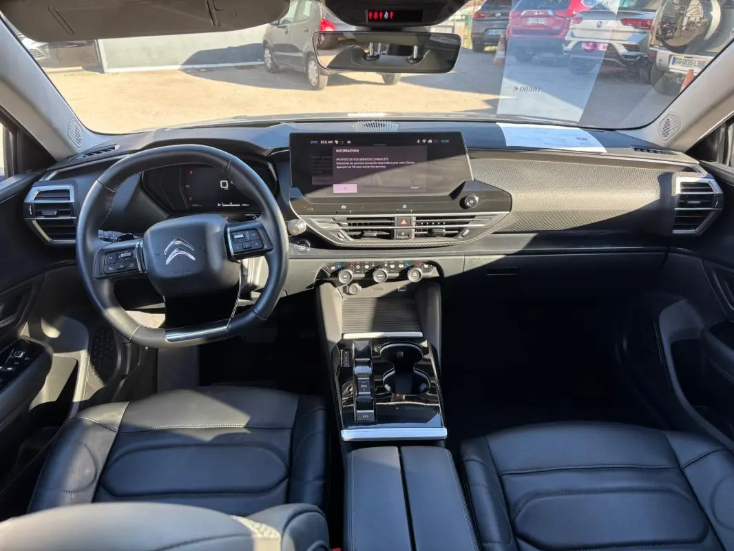 Vue intérieure avant de la Citroën C5 X 2024, tableau de bord moderne avec écran tactile et volant cuir noir.