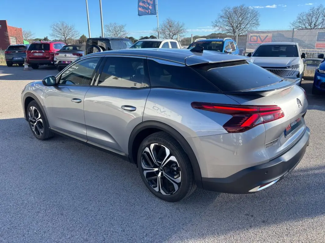 Vue 3/4 arrière droite d'une Citroën C5 X gris foncé avec jantes alliage 19 pouces et toit noir contrasté.