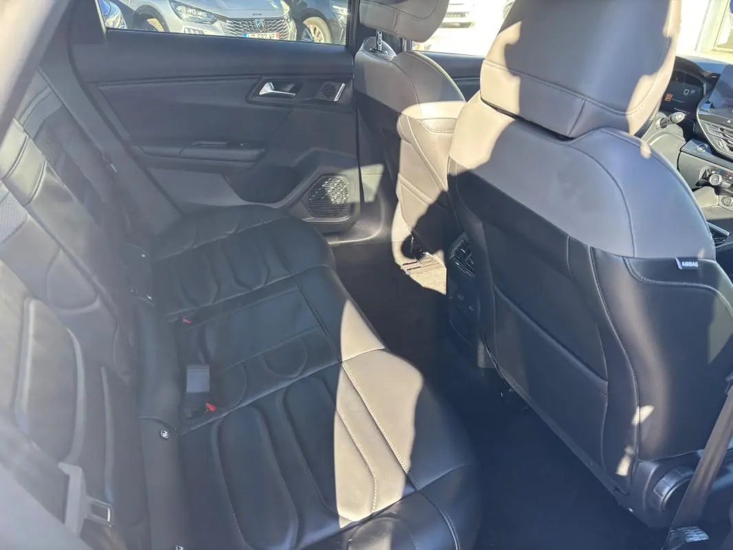 Vue intérieure arrière côté gauche d’une Citroën C5 X 2024 avec sièges en cuir noir et accoudoir central.