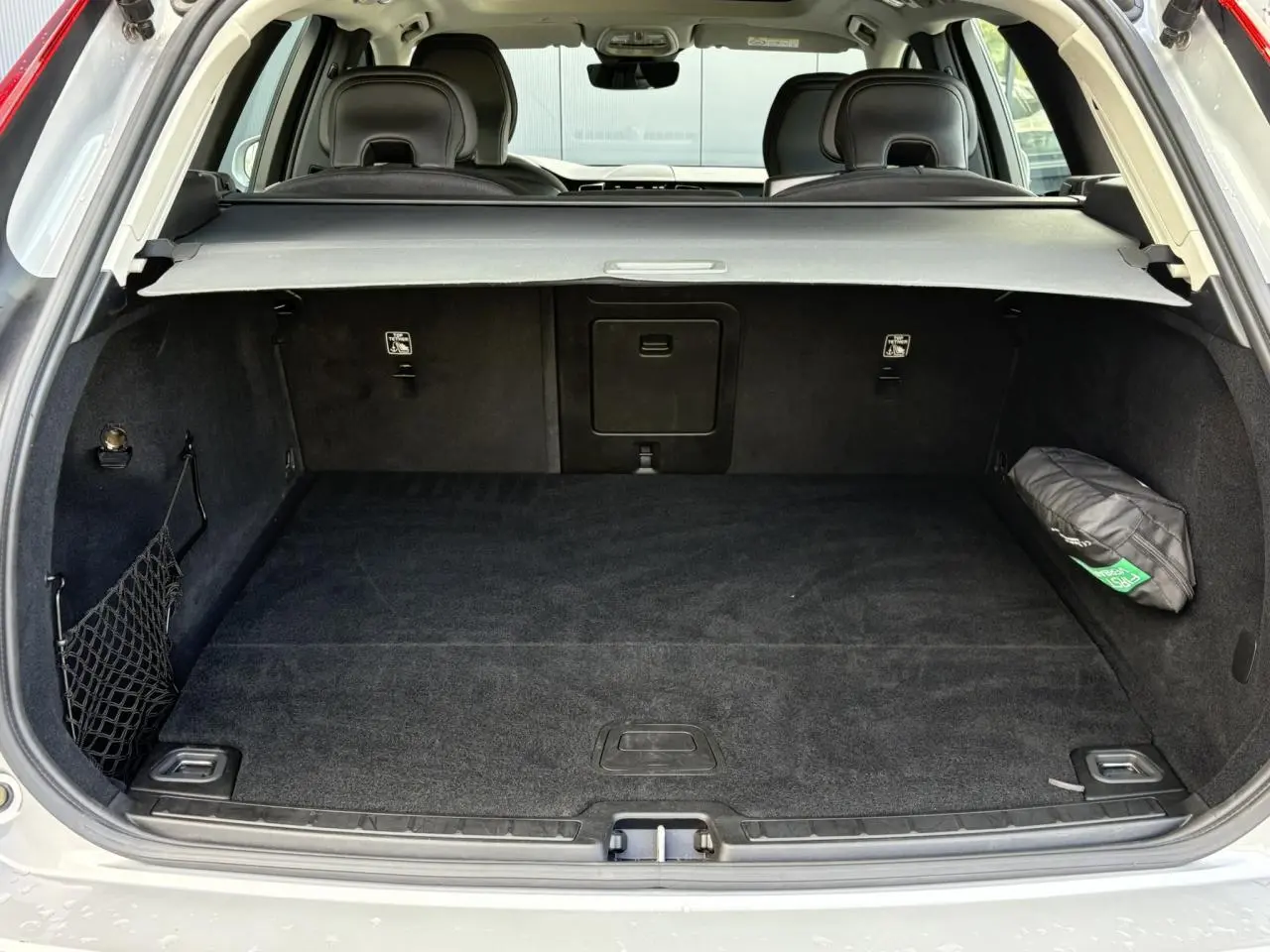 Coffre ouvert du Volvo XC60 gris silver, vue arrière montrant l’espace de chargement et la plage arrière rétractable.