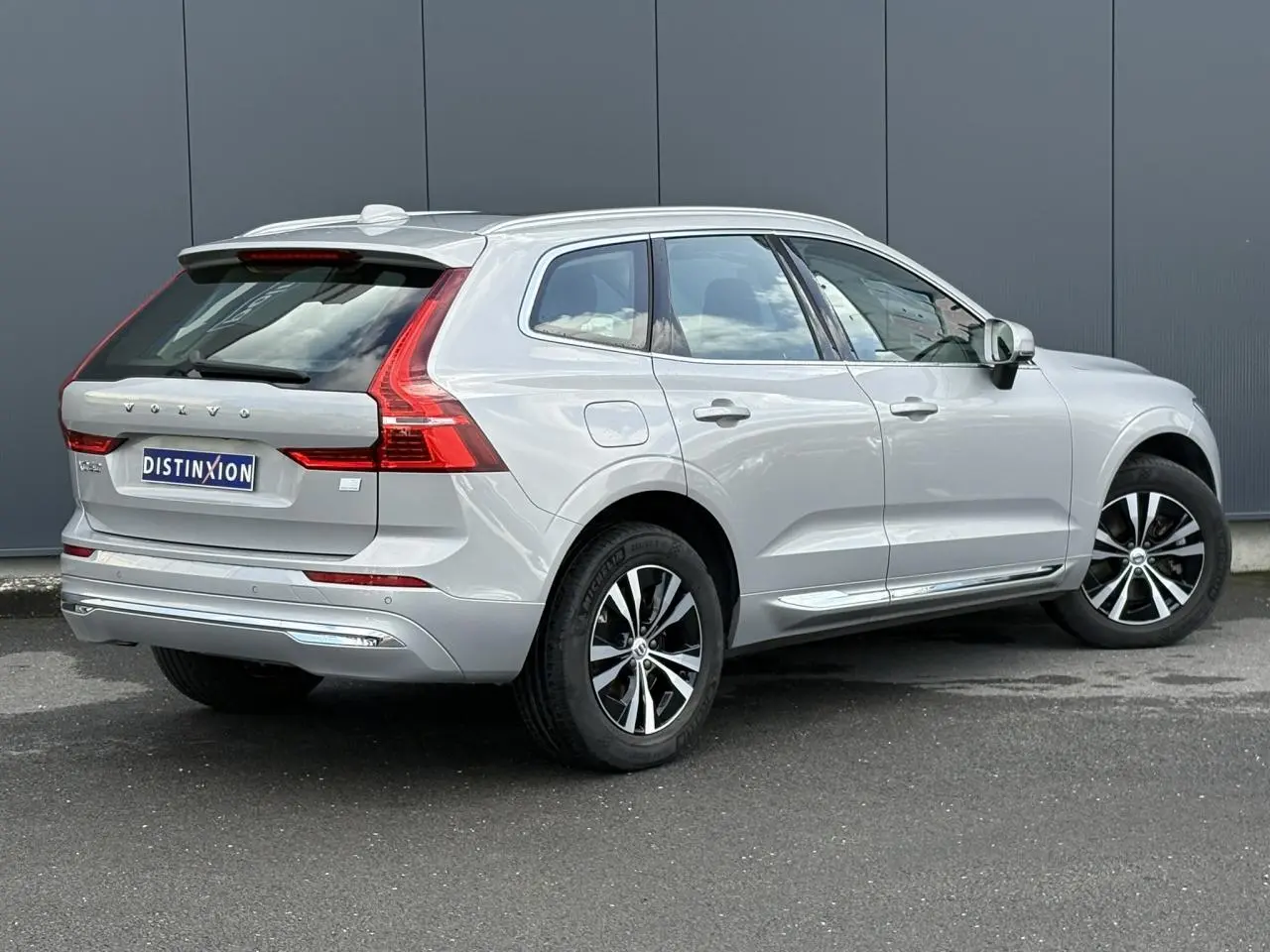 Vue 3/4 arrière droite d'un Volvo XC60 gris silver 2024 avec jantes alliage et vitres teintées.