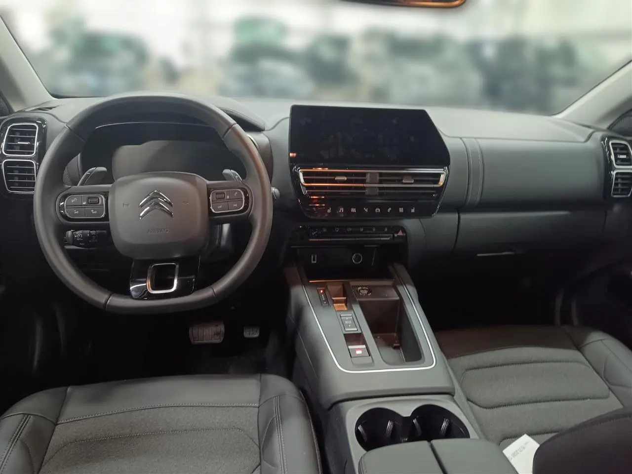 Vue intérieure avant du Citroën C5 Aircross Hybrid noir Perla, avec tableau de bord moderne et écran tactile central.