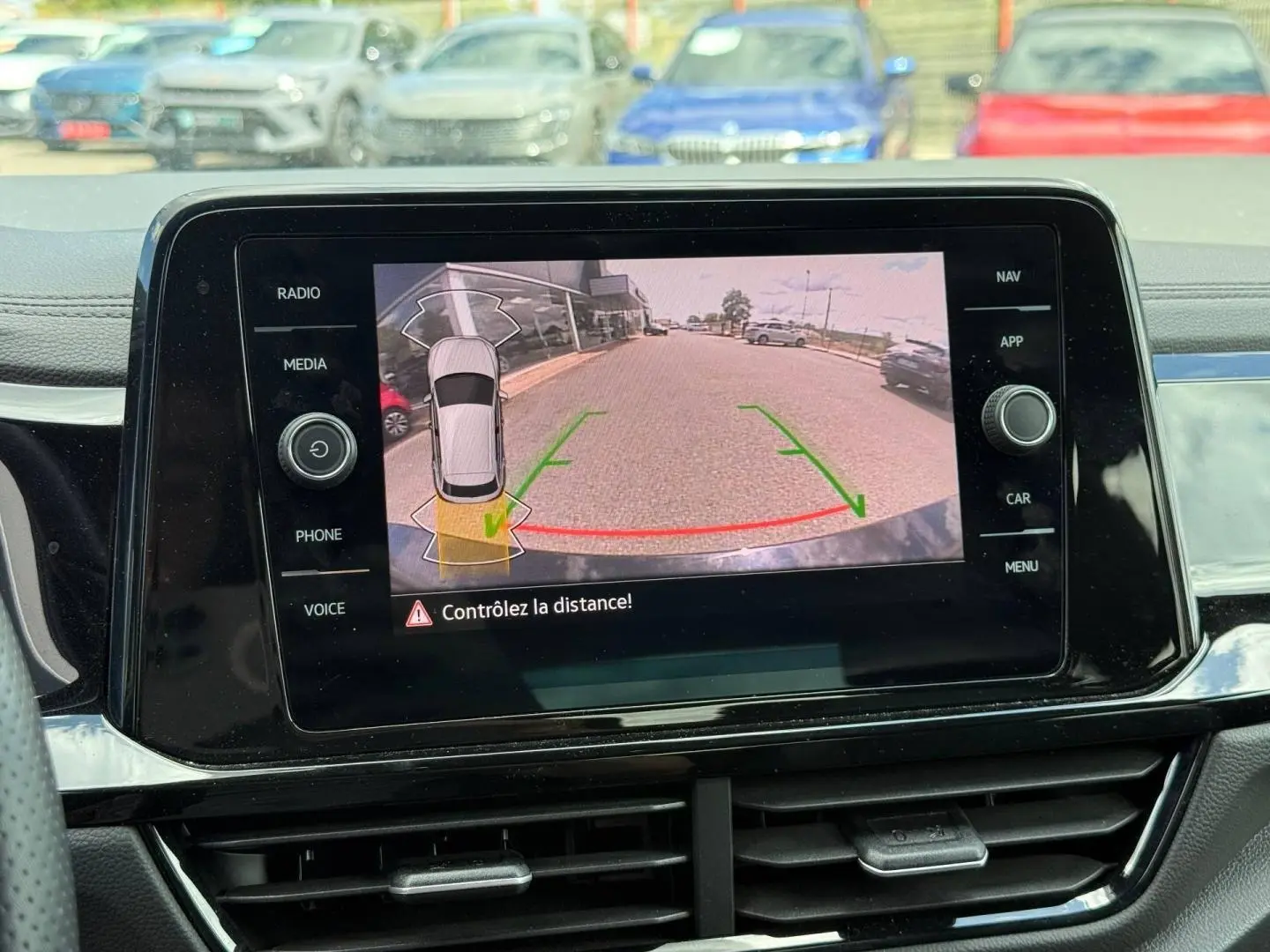 Vue intérieure sur l'écran tactile affichant la caméra de recul du Volkswagen T-Roc noir intense nacré, avec guidage de trajectoire.