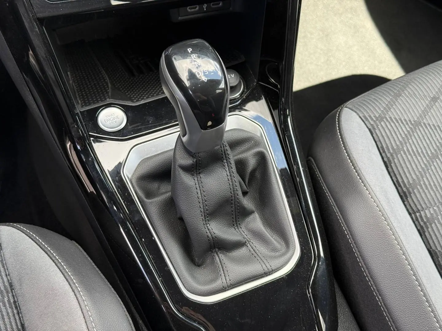 Le levier de vitesse automatique noir et cuir du Volkswagen T-Roc 1.5 TSI Evo2, vu en gros plan intérieur.