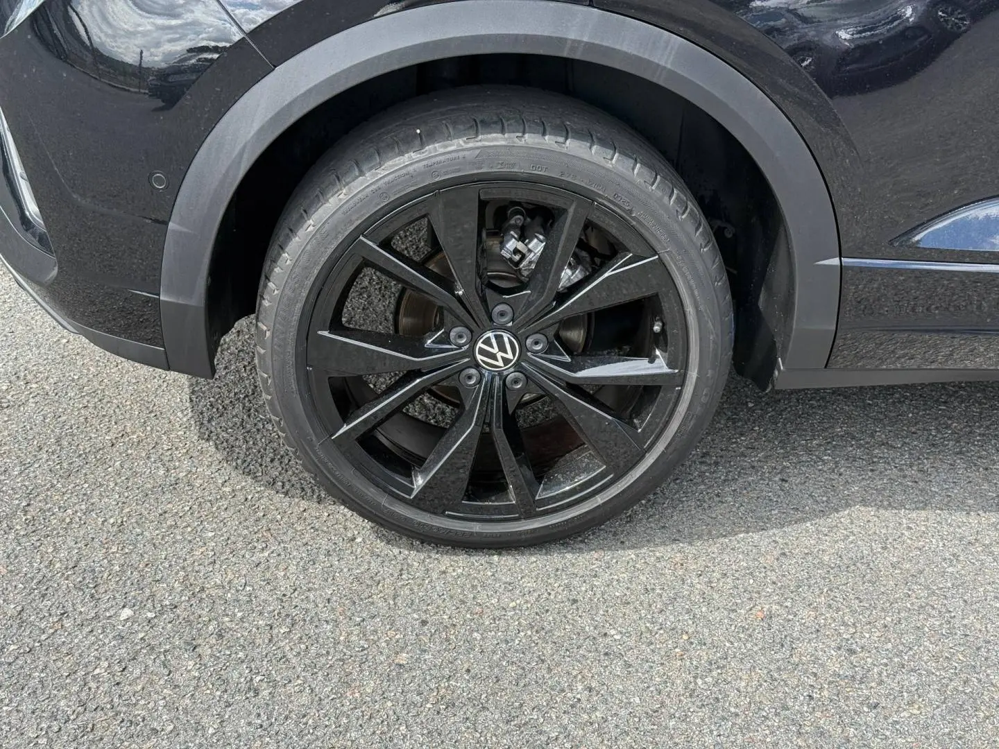 Gros plan sur la roue arrière droite noire brillante du Volkswagen T-Roc noir intense nacrée avec jante alu R-Line.