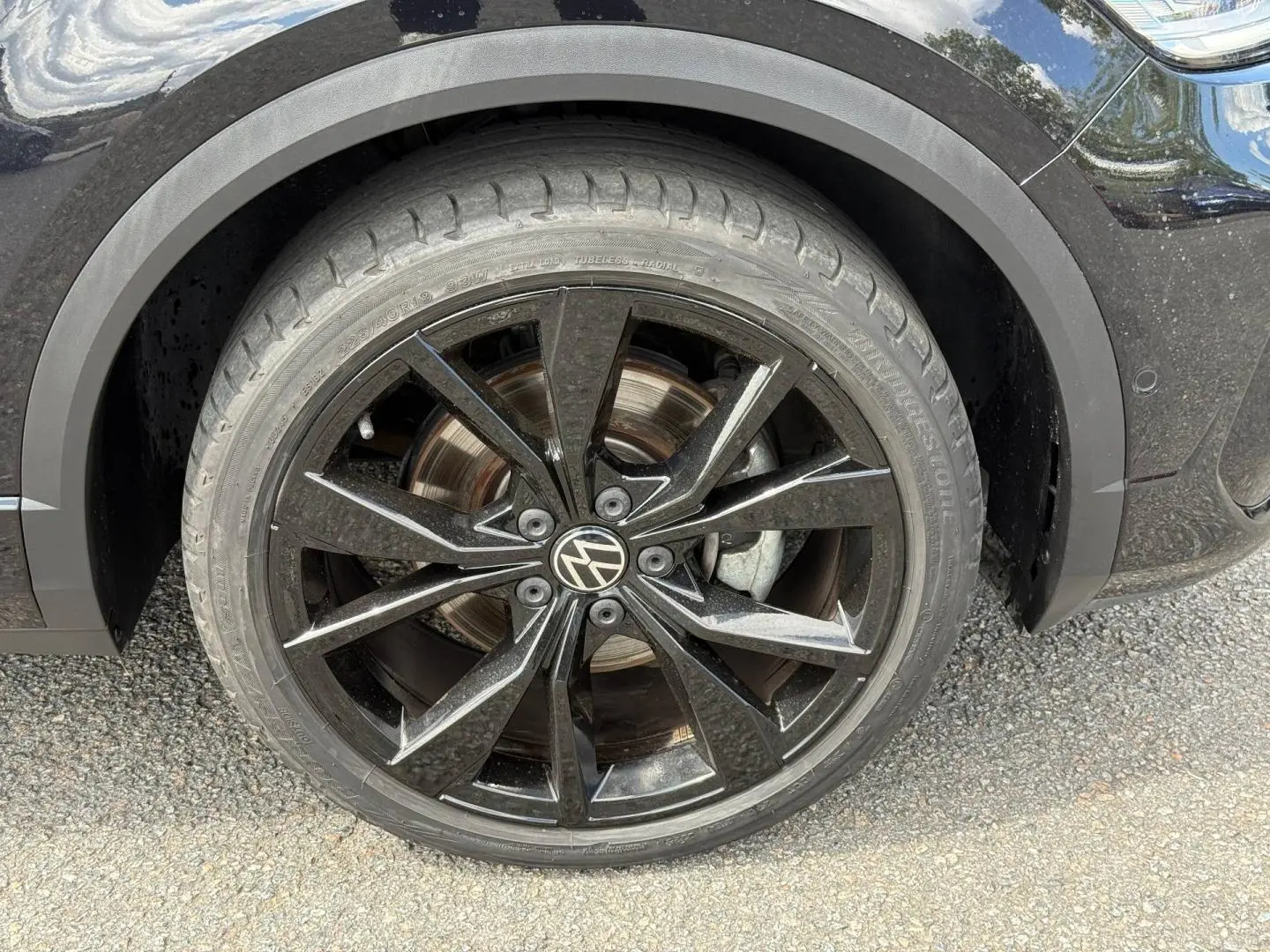 Gros plan sur la roue avant gauche noire avec jante alu noire du Volkswagen T-Roc Noir Intense nacrée 2025.