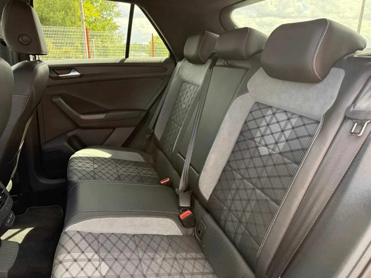 Vue latérale intérieure des sièges arrière du Volkswagen T-Roc 2025 avec sellerie mixte noire et grise à motifs géométriques.