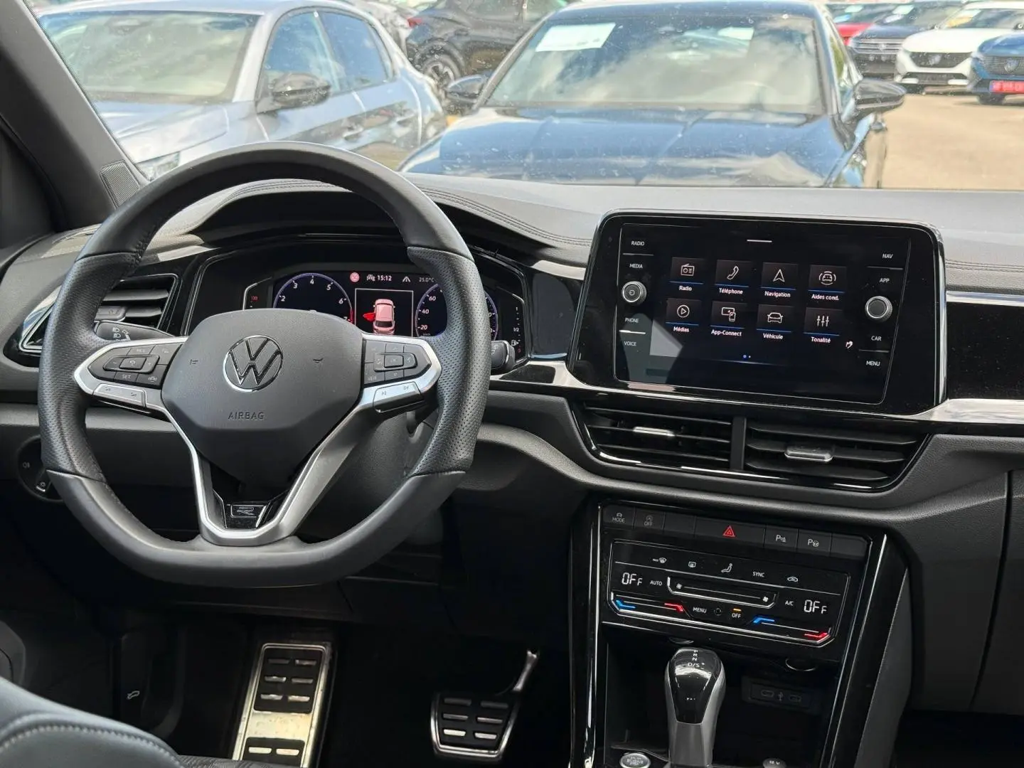 Vue intérieure du tableau de bord du Volkswagen T-Roc 2025, volant cuir multifonction et écran tactile central.