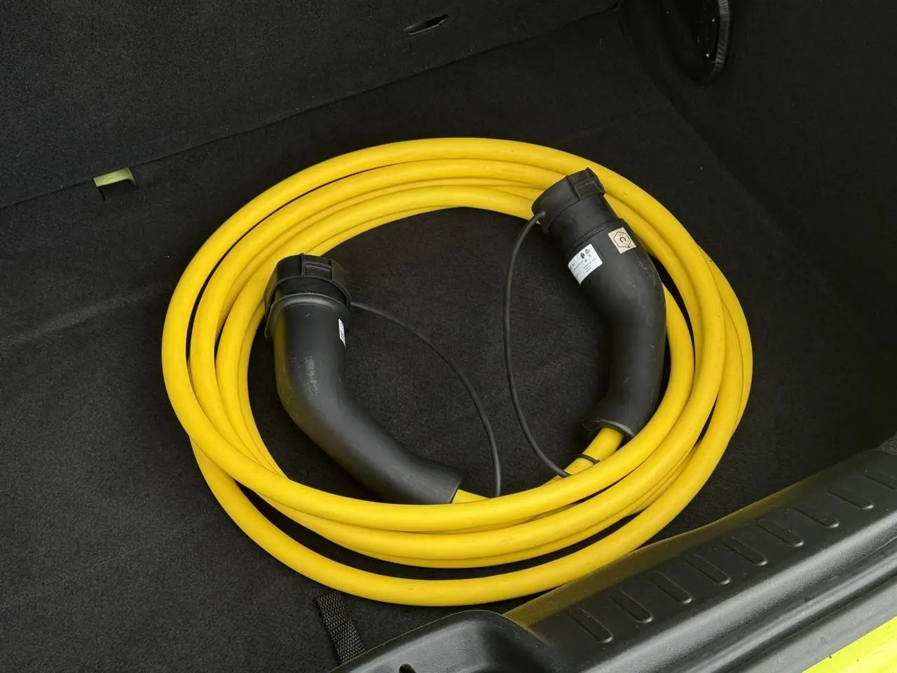 Câble de recharge électrique jaune enroulé dans le coffre d'une FIAT 500 Electrique Jaune Acid 2024.