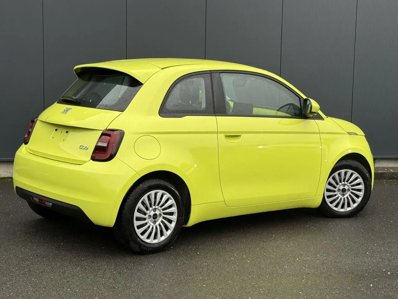 Fiat 500 électrique jaune Acid vue 3/4 arrière côté droit, avec jantes alliage et feux arrière LED foncés.