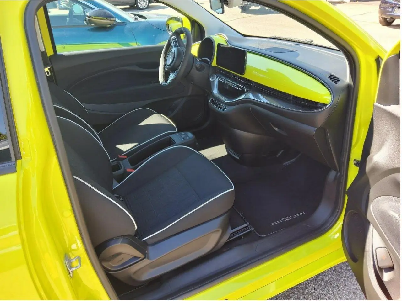 Intérieur côté conducteur d'une FIAT 500 électrique 2024 jaune Acid, avec tableau de bord et sellerie noire contrastée.