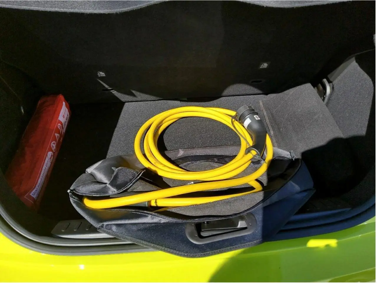 Coffre ouvert d’une FIAT 500 électrique jaune Acid avec câble de recharge jaune enroulé visible.