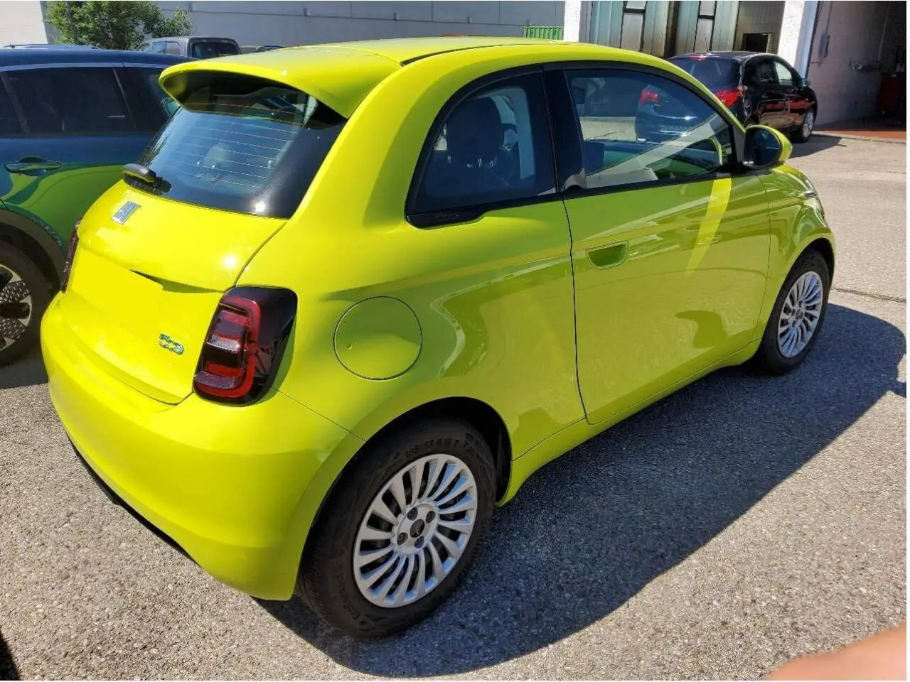 Vue 3/4 arrière droite d'une FIAT 500 électrique 2024 en jaune Acid avec feux arrière LED et jantes blanches.