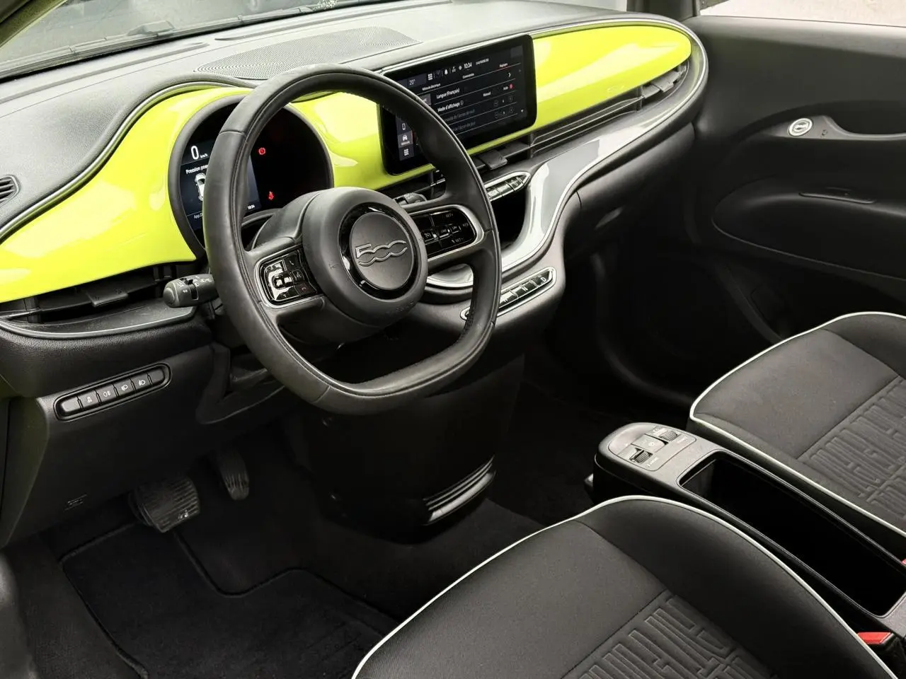 Intérieur avant droit de la Fiat 500 électrique 2024 avec tableau de bord jaune Acid et sièges tissu noir.