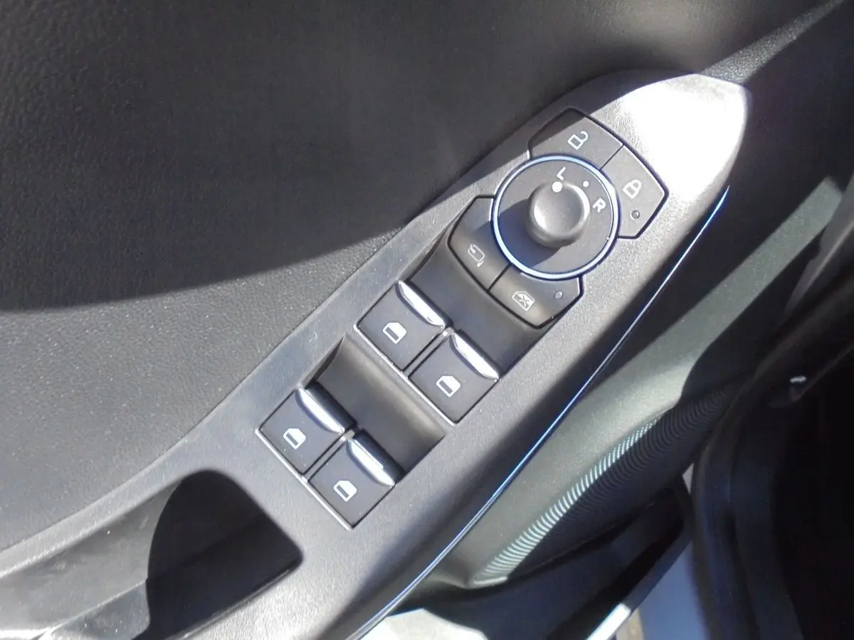 Gros plan sur les commandes de lève-vitres et rétroviseurs côté conducteur d'une Ford Puma gris Solar Metal.