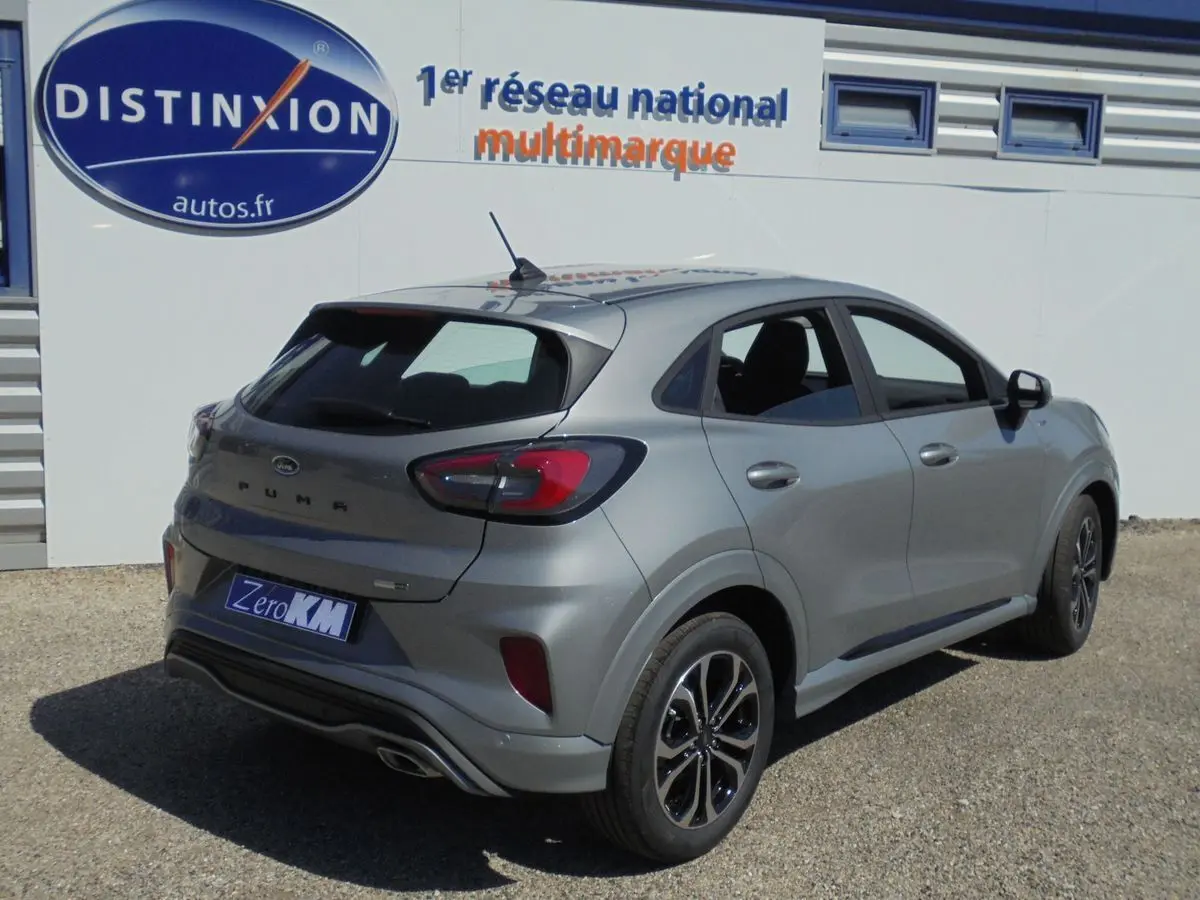 Ford Puma 1.0 EcoBoost hybride gris Solar Metal vu en 3/4 arrière côté droit, avec jantes noires et toit noir.